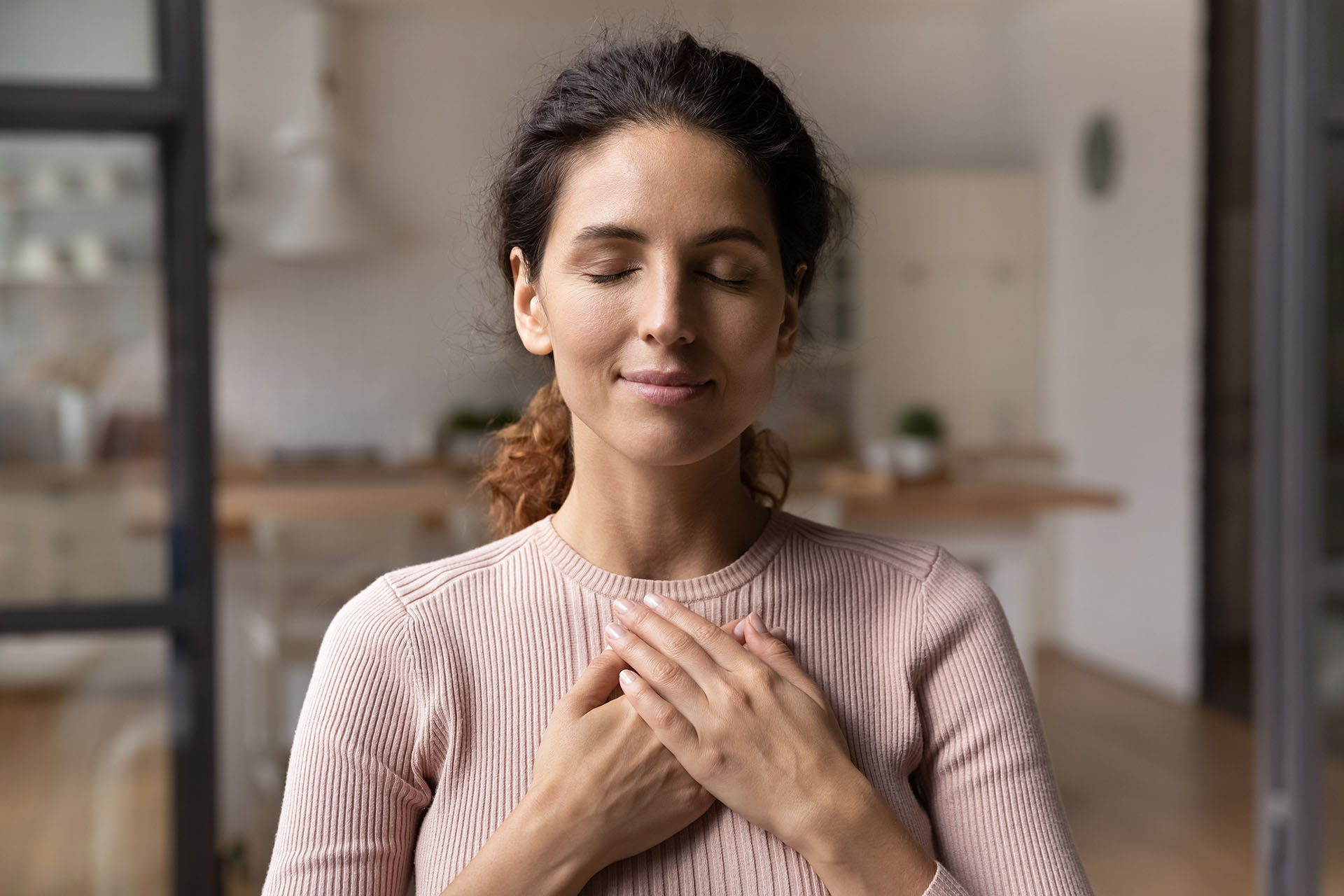 Calm young woman hold hands on chest