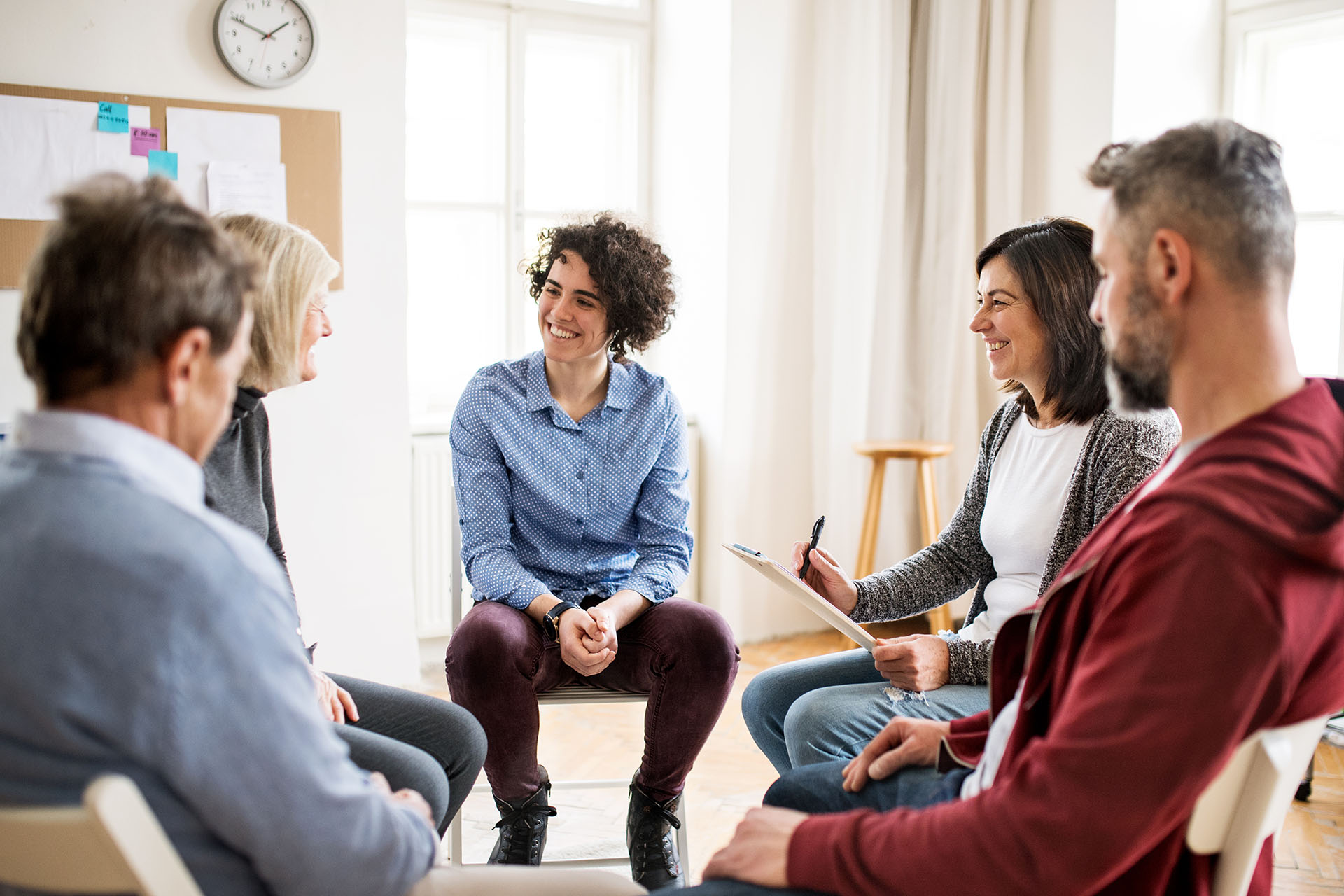 Men and women sitting in a circle during group therapy, talking.