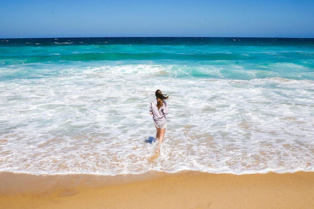 Woman putting her feet in the ocean representing how freeing and hopeful drug rehab at Breakaway Health in Costa Mesa, California can be.