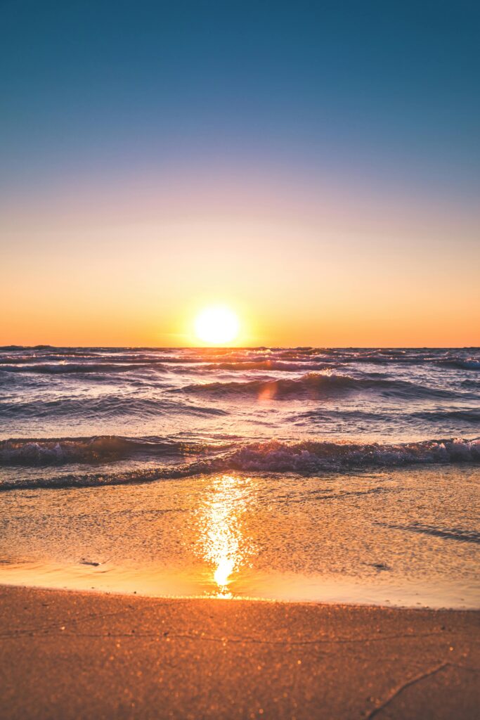 California beach at Sunset with the sun setting on the horizon.