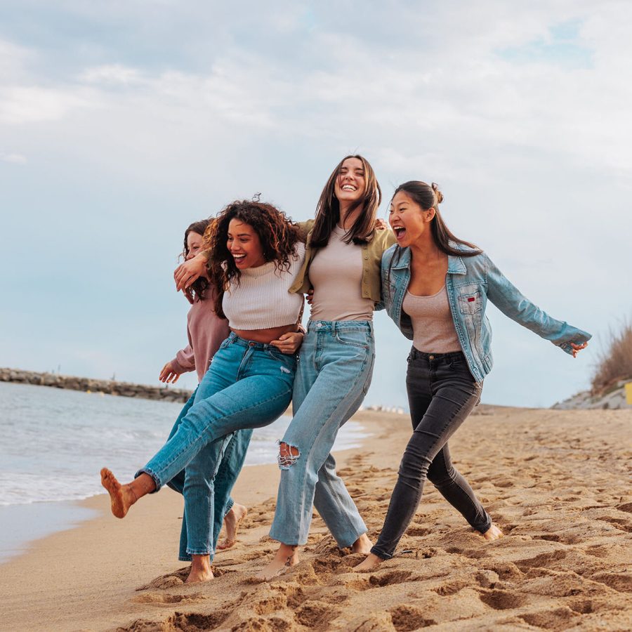 Four young women jumping together on beach